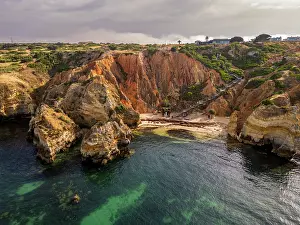Birds Prints: Sunset over beach cliffs with rocky shoreline in Algarve region of Portugal