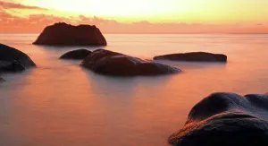Orange Prints: Sunset at Beau Vallon beach, with rocky formations and calm waters in Seychelles