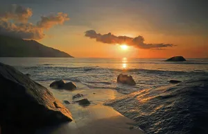Retreat Prints: Sunset at Beau Vallon beach with waves gently lapping against rocks in Mahe, Seychelles