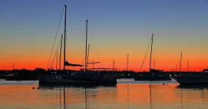 Silhouettes Prints: Sunset over boats in the water with colors reflecting in Grand Baie