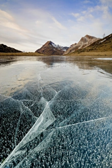 Sunset on the frozen Lej Nair surrounded by rocky peaks, Bernina Pass, Canton of Graubunden