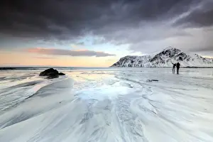 Unrecognisable Person Prints: Sunset and hikers on Skagsanden beach surrounded by snow covered mountains, Flakstad