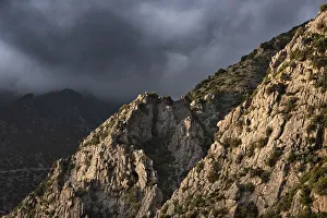 Chefchaouen Prints: Sunset light on a rocky mountain and dark clouds in the sky, Chefchaouen, Morocco