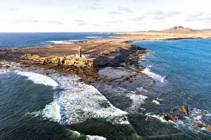Sunset over the lighthouse of Punta Jandia (Faro de la Lola) washed by ocean waves