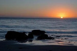 Back Lit Prints: Sunset over the ocean, with rocks in the foreground