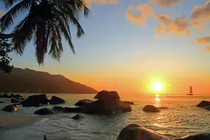 Adventures Prints: Sunset over the ocean with rocks and a sailboat at Beau Vallon Beach in Seychelles