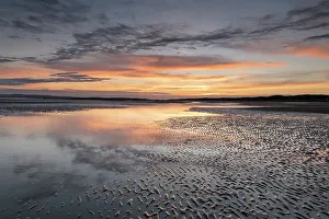 Reflective Prints: Sunset reflections on sandy beach at sunset