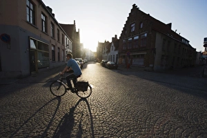 Bicycles Prints: Sunset and shadow of a cyclist on cobbled street, old town, UNESCO World Heritage Site
