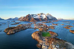 Stadium Prints: Sunset over the small village of Henningsvaer surrounded by snowy massif with the famous soccer field in the foreground