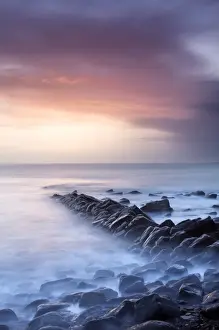 Sunset on a stormy winters day looking across Kimmeridge Bay from the remains of Clavells Pier, Kimmeridge, near Swanage, Dorset, England, United