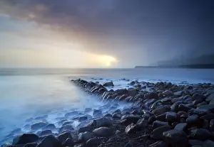 Swanage Prints: Sunset on a stormy winters day looking across Kimmeridge Bay from the remains of Clavells Pier