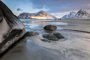 Sunset on the surreal Skagsanden beach surrounded by snow covered mountains, Flakstad