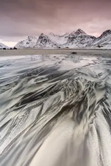 Sunset on the surreal Skagsanden beach surrounded by snow covered mountains, Flakstad