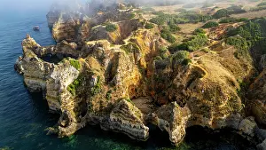 Land Prints: Sunset view of beach cliffs near Lagos in Algarve Portugal with ocean and land meeting at dusk