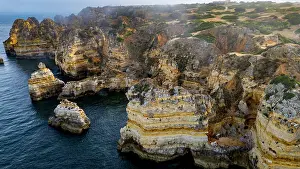 Wonders Prints: Sunset view of beach cliffs with ocean waves in Algarve region of Portugal near Lagos city