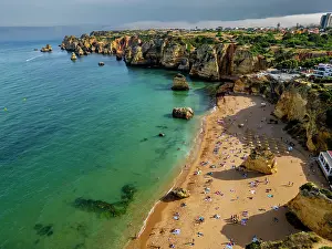 Enjoyment Prints: Sunset view of beach cliffs and sandy shore in Algarve with people enjoying the evening by the water