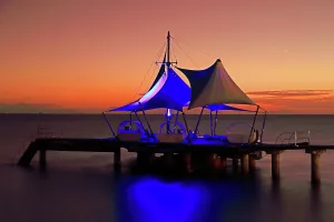 Watercraft Prints: Sunset view from Coco de Mer hotel showing the pier and illuminated tent structures