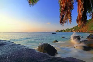 Crashing Prints: Sunset view over rocks by Beau Vallon beach with gentle waves at Mahe, Seychelles
