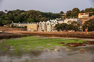 Seashore Prints: Sunset view of St Peter Port harbourfront with houses and tidal flats on the Channel Islands