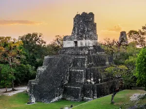 Pyramid Prints: Sunset view of Temple II in Great Plaza of Tikal showcasing the ancient architecture and surrounding trees