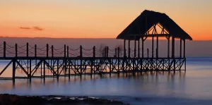 Retreat Prints: Sunset view over a wooden pier with a thatched roof on the coast of Mauritius
