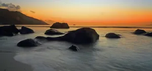 Hour Prints: Sunset over the water with rocks at Beau Vallon beach