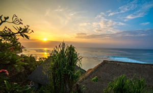 Thatched Roof Prints: Surfers at sunset in Bali with straw roofed huts, Indonesia, Southeast Asia, Asia