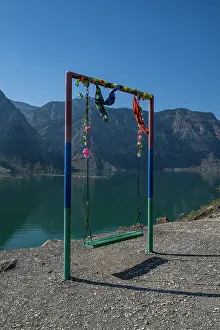Hanging Prints: Swing set by the river with flowers and mountains in the background near Dagestan, Russia