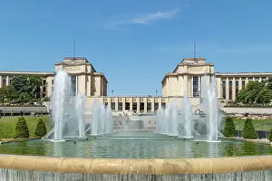 Water Feature Prints: Symmetrical view of a grand fountain with water jets in front of a classical building under a clear blue sky