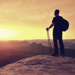 Rock Cliff Prints: Tall ginger hair hiker in t-shirt and dark trekking trousers on cliff