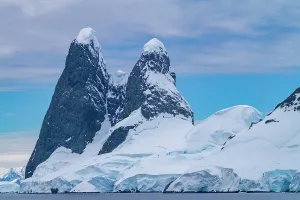 Navigation Prints: Tall rock formations rise above icy waters in the Lemaire Channel in Antarctica during a cloudy day in winter