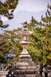 Harmony Prints: Tall stone lantern in front of warm green Trees. Japan