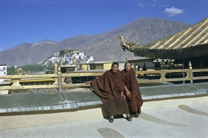 Two Tibetan Buddhist monks at Jokhang temple, with the Potala palace behind