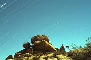 Time Exposure Prints: Time exposure of stars streaking across the sky with rock formations in the foreground