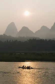 Tourist boat sailing through karst scenery at sunrise on the Li river