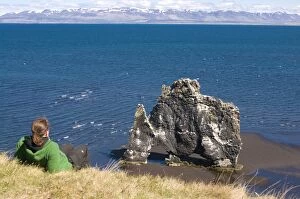 Tourist relaxing at the famous Hvitserkur rock formation, Vatnsnes Peninsula