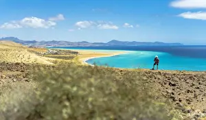 Tourist with straw hat looking at the ocean from Mirador Del Salmo viewpoint, Costa Calma