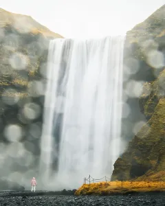 Females Prints: Tourist wear pink jacket stand by beautiful dramatic famous Skogafoss waterfall in Iceland in spring