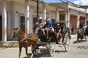 Tourists enjoying a horse-drawn buggy ride through Moron, Ciego de Cvila