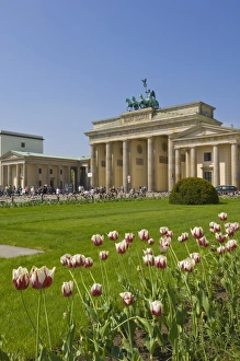 Tourists enjoying spring sunshine in the tulip filled gardens at the Brandenburg Gate with the Quadriga winged victory Tourists enjoying spring sunshine in the tulip filled gardens at the Brandenburg Gate with the Quadriga winged victory