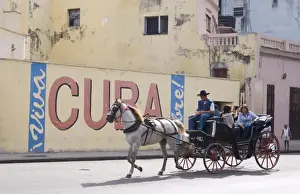 Carriage Prints: Tourists in a horse carriage passing a wall sign saying Live free Cuba