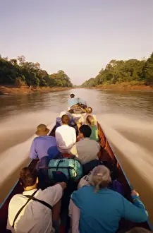 Mulu Prints: Tourists in longboat on a river in the Mulu National Park in Sarawak