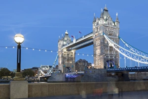 Lamp Post Prints: Tourists and passers by stop to take pictures of Tower Bridge at dusk