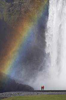 Tourists in red jacket at 62 m high Skogafoss waterfall, Skogar, South area Tourists in red jacket at 62 m high Skogafoss waterfall, Skogar, South area