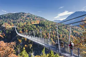 Tourists on the suspension bridge called Highline 179 framed by colorful woods in autumn