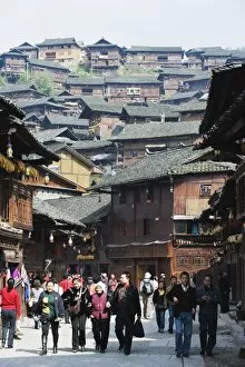 Tourists walking by wooden houses on the old streets of Xijiang, Guizhou Province