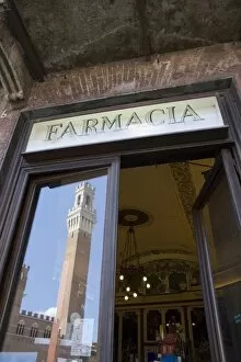The tower of Palazzo Pubblico reflected in Farmacia window, Piazza del Campo
