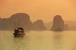 L Imestone Prints: Traditional boat sailing through limestone archipelago at sunset