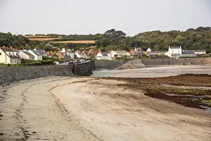 Guernsey Prints: Traditional houses by Rocquaine Bay at low tide with stone seawall in Guernsey Channel Islands