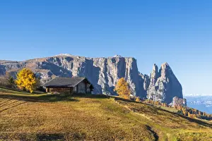 Traditional huts at Alpe di Siusi (Seiser Alm) in autumn with Sciliar peaks in background